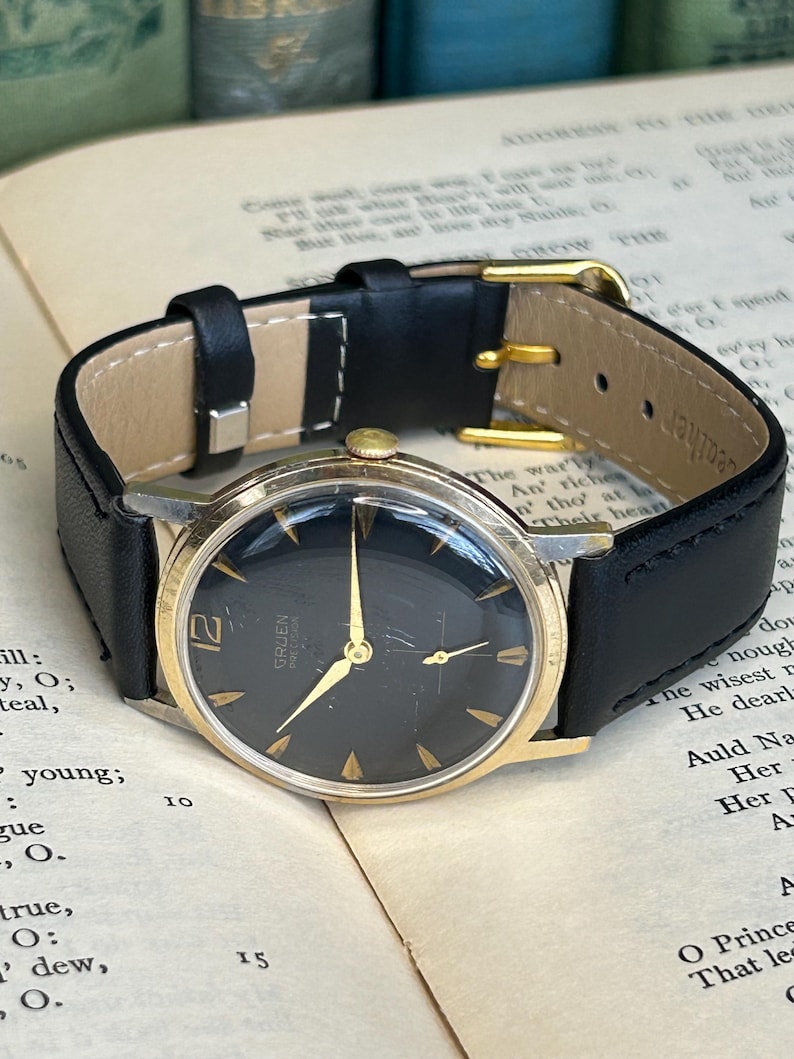 Vintage 1960s Gruen Precision watch.  Black leather band.  Running, serviced, keeps time, working.  Gold plated case with black dial