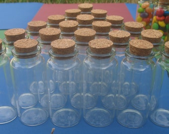 Peut inclure: Un groupe de 18 bouteilles en verre transparent avec des bouchons en liège. Les bouteilles sont disposées en forme de triangle sur une surface bleue.