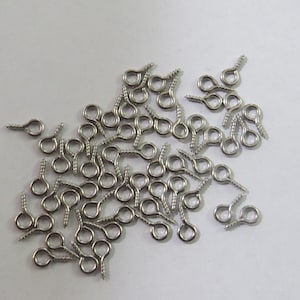 Puede incluir: Un montón de ganchos de ojal de tornillo de color plateado. Estos pequeños ganchos de metal son ideales para sujetar joyas, abalorios u otros artículos pequeños a proyectos.