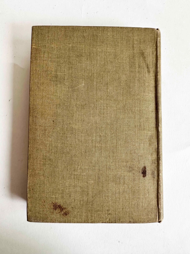 May include: A vintage book with a textured, olive-green cover. The cover shows signs of wear, including stains and discoloration. The spine is a darker shade of brown. The book is rectangular and appears to be closed.