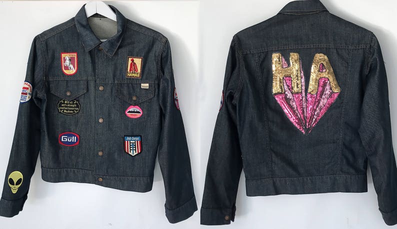 Peut inclure: Une veste en jean bleu fonc&eacute; avec divers patchs et embellissements. Le dos de la veste pr&eacute;sente un grand c&oelig;ur en sequins rose et or avec les lettres "HA" en sequins dor&eacute;s.