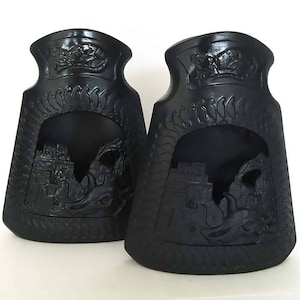 以下が含まれることがあります： 複雑なデザインが施された黒いセラミック製の暖炉用薪置き2個。それぞれの置き場は、城とドラゴンが浮き彫りになっている。