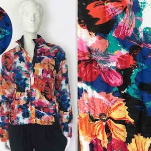 May include: A colorful floral print jacket with a stand-up collar and a zipper closure. The jacket features a vibrant pattern of red, pink, orange, blue, and green flowers on a white background. The jacket is displayed on a mannequin.