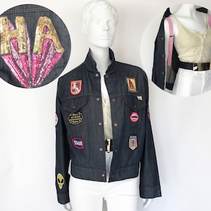 May include: A dark blue denim jacket with various patches, including a sequined patch that says "HA", a red patch with a horse, a red patch with a lips design, a blue patch with a "Goll" logo, and a red, white, and blue patch with a star design.