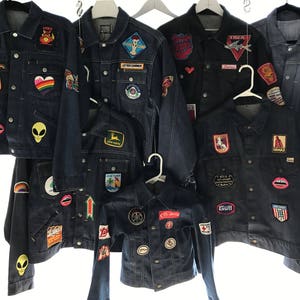 Peut inclure: Une collection de dix vestes en jean avec diff&eacute;rents patchs et motifs. Les vestes sont toutes de couleurs et de styles diff&eacute;rents, certaines ont des patchs brod&eacute;s, tandis que d'autres ont des patchs thermocollants. Les vestes sont toutes en bon &eacute;tat et seraient un excellent ajout &agrave; toute garde-robe.