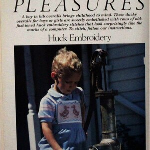 May include: A young child wearing blue overalls with a pink and white duck embroidery design stands by a hand pump. The overalls have a bib with two ducks embroidered on it. The child is looking down at the pump handle. The text "SIMPLE PLEASURES" is at the top of the image. The text "Huck Embroidery" is below the image.