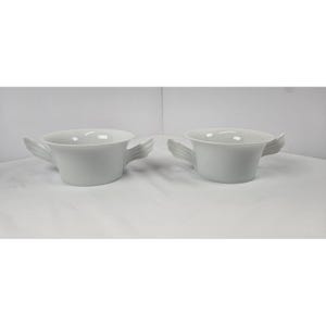 May include: Two white ceramic bowls with wing-shaped handles. The bowls have a simple, elegant design, perfect for serving soups or desserts. The wing handles add a unique and artistic touch to the tableware.