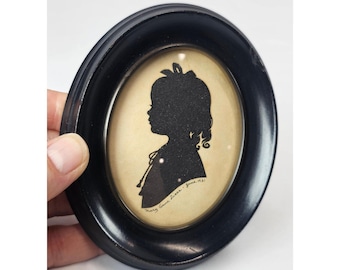 Retrato de silueta de niña pequeña, tallado a mano, estilo vintage de 1931, con marco ovalado y cristal convexo.
