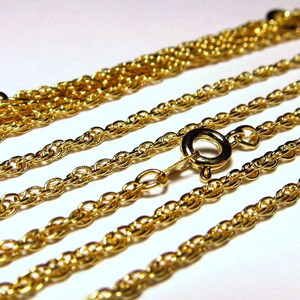 May include: Four gold chains of different thicknesses, with a clasp on one of the chains.