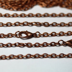 May include: Four strands of copper chain with lobster claw clasps. The chain is a simple, round link style.