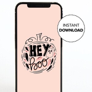 Może przedstawiać: Smartfon wyświetla różowy ekran z motywem Halloween. Projekt zawiera słowa "HEY boo" w ozdobnej czcionce, kontur dyni i ducha. Naklejka z boku mówi "NATYCHMIASTOWE POBIERANIE".