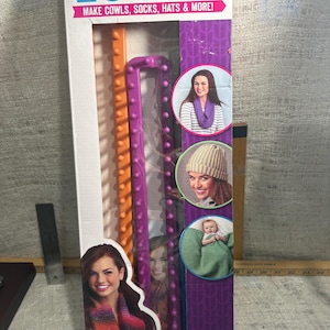 May include: A rectangular loom set for making cowls, socks, hats, and more. The package features orange and purple looms, with images of finished projects. Text on the package reads "RECTANGLE LOOMS" and "MAKE COWLS, SOCKS, HATS & MORE!"