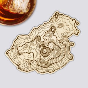 Könnte beinhalten: Ein Holzuntersetzer mit einem topografischen Kartendesign von Hualalai, Hawaii. Der Untersetzer hat dunkelbraune Konturlinien auf hellem Holzgrund. Der Text "HUALALAI • HAWAII, HI" ist auf dem Untersetzer aufgedruckt.