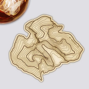 Könnte beinhalten: Ein Untersetzer aus Holz mit einer topografischen Karte des Mt. Bierstadt und dem Text "MT. BIERSTADT-CO". Der Untersetzer ist hellbraun mit dunkelbraunen Konturlinien.