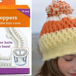 Puede incluir: Dos toppers de telar de plástico blanco para un telar de punto doble giratorio. Los toppers de telar están en una caja con acentos naranja y morado. El texto en la caja dice "Loom Toppers for Rotating Double Knit Loom" y "Now bigger knits on same base! (2) 60 peg looms".