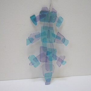 K&ouml;nnte beinhalten: Ein blauer und violetter Glasanh&auml;nger aus vielen kleinen Glassplittern. Der Anh&auml;nger ist baumf&ouml;rmig und hat eine silberne Schnur zum Aufh&auml;ngen.