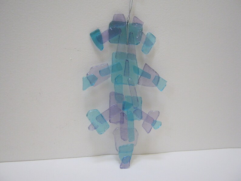 K&ouml;nnte beinhalten: Ein blauer und violetter Glasanh&auml;nger aus vielen kleinen Glassplittern. Der Anh&auml;nger ist baumf&ouml;rmig und hat eine silberne Schnur zum Aufh&auml;ngen.