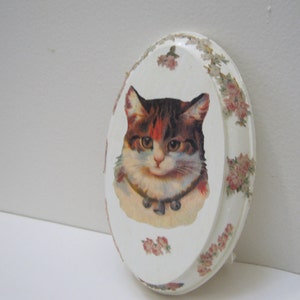 May include: White oval ceramic trinket dish with a floral border and a vintage image of a cat with a collar and bell.