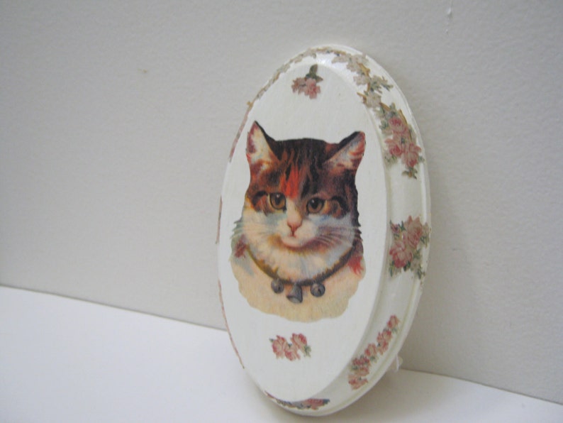 May include: White oval ceramic trinket dish with a floral border and a vintage image of a cat with a collar and bell.