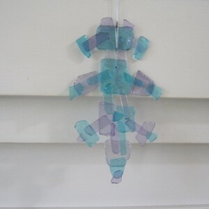 K&ouml;nnte beinhalten: Ein blauer und violetter Glaswindspiel mit mehreren Glasst&uuml;cken, die an einer Schnur h&auml;ngen. Die Glasst&uuml;cke haben die Form von Rechtecken und Quadraten.