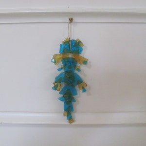 May include: A blue and gold glass ornament hanging from a white ceiling. The ornament is made of many small pieces of glass that are arranged in a geometric pattern.