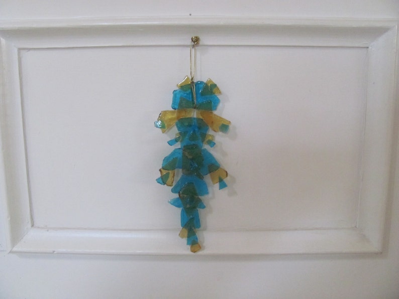 May include: A blue and gold glass ornament hanging from a white ceiling. The ornament is made of many small pieces of glass that are arranged in a geometric pattern.
