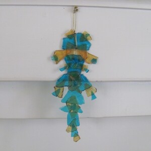 May include: A blue and gold glass ornament shaped like a seahorse. The ornament is made of many small pieces of glass that are glued together.