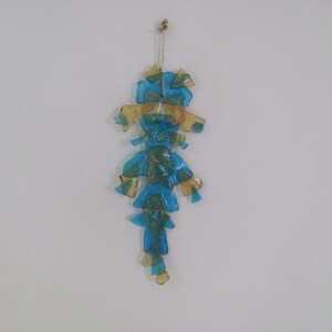 May include: A blue and gold glass mobile with a teardrop shape hangs from a white ceiling.