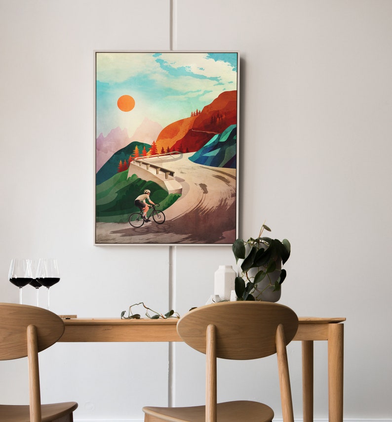 Pu&ograve; includere: Un dipinto astratto colorato di un ciclista che sale su una strada tortuosa attraverso un passo di montagna. Il cielo &egrave; blu con un sole arancione brillante. Le montagne sono un mix di verde, rosso e blu.