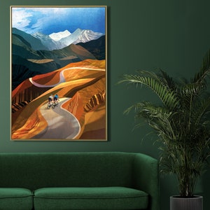 May include: A framed print of a colourful landscape painting featuring two cyclists riding up a winding road through a mountain pass. The sky is blue with white clouds and the mountains are a mix of brown, green, and yellow.