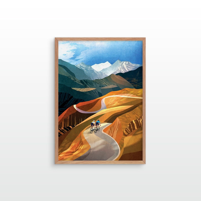 May include: Two cyclists ride up a winding road through a mountain pass. The road is paved and surrounded by brown and green hills. The mountains in the background are snow-capped.