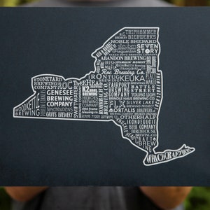 May include: A black and white graphic of the state of New York with the names of breweries in the state. The graphic is on a dark blue background.