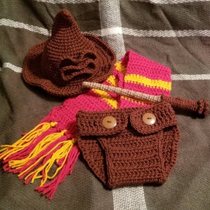 May include: A brown crochet baby outfit set, including a Sorting Hat, scarf with red and yellow stripes, a wand, and diaper cover. The set is designed with a Harry Potter theme.
