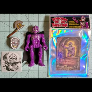 May include: A purple plastic skeleton action figure with a black cape, a silver and brown axe, a silver skull-shaped shield, a circular sticker, and a holographic packaging bag labeled PHANTOM ZERO SKELETON with an illustration of the figure.