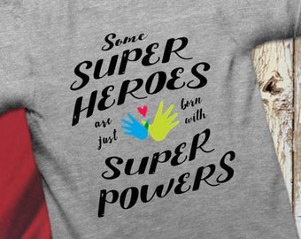 May include: Gray t-shirt with a black graphic that reads "Some Super Heroes are just born with Super Powers". The graphic includes two hands with a heart in the middle.