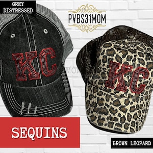 May include: Two trucker hats with the letters "KC" in red with sequins. One hat is grey distressed denim and the other is brown leopard print.