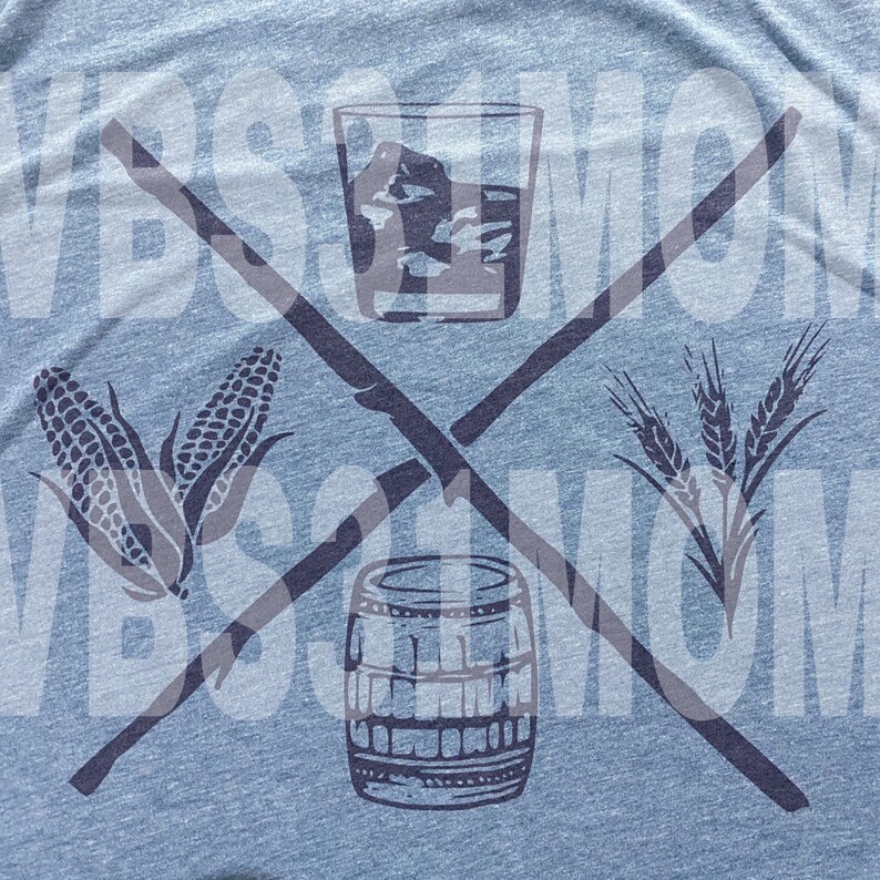 May include: Light blue t-shirt with a graphic design featuring a crossed stick design. The design includes a glass of whiskey with ice, corn, a barrel, and wheat. The text "VBS MOM" is faintly visible.