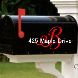 May include: Black mailbox with a red flag and a white post. The mailbox has a white address label with the text "425 Maple Drive" and a red cursive letter "B".