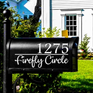 May include: Black mailbox with the address 1275 and the street name "Firefly Circle" in white script. The mailbox is in front of a white house with black shutters and a green lawn.