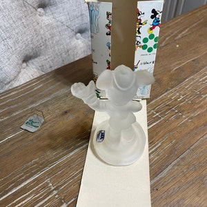 May include: A clear glass figurine of Mickey Mouse wearing a pirate hat and holding a sword. The figurine is on a clear glass base and is in a white box with a green and white pattern. The box has the text "Walt Disney" and "Made in Italy" on it.