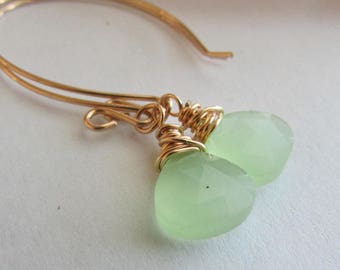 Puede incluir: Pendientes de alambre dorado envueltos con gotas de piedras preciosas verde claro.
