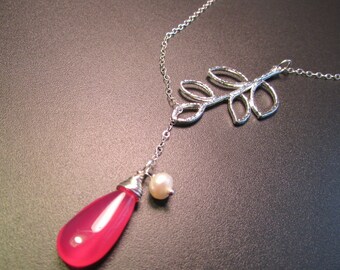 May include: A silver necklace with a delicate branch design and a pink teardrop-shaped stone pendant. A small white pearl hangs below the stone.