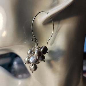 May include: Silver dangle earrings with a cluster of gray pearls.