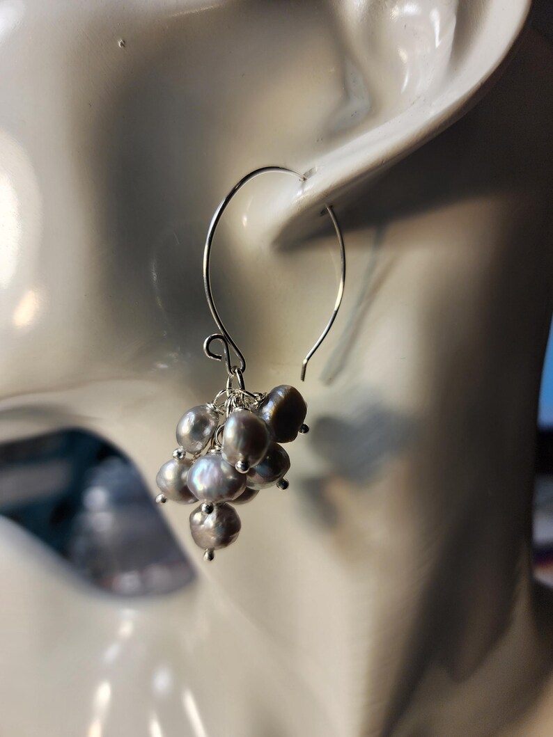 May include: Silver dangle earrings with a cluster of gray pearls.