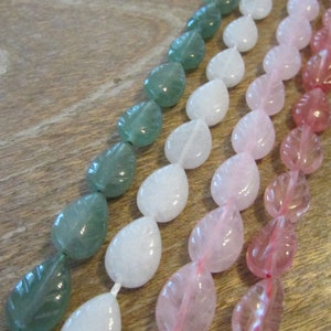May include: Three strands of gemstone beads in leaf shapes. The beads are green, white, and pink.