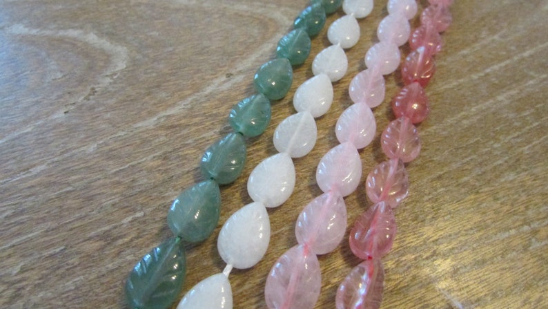May include: Three strands of gemstone beads in leaf shapes. The beads are green, white, and pink.