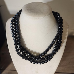 May include: A triple strand black pearl necklace. The pearls are round and smooth.