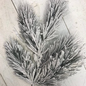 May include: A snowy pine sprig with a wire stem, perfect for adding a touch of winter to your holiday decor.