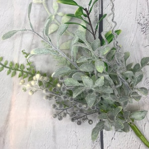 May include: A bunch of artificial greenery with a mix of green and white leaves and small gray berries.