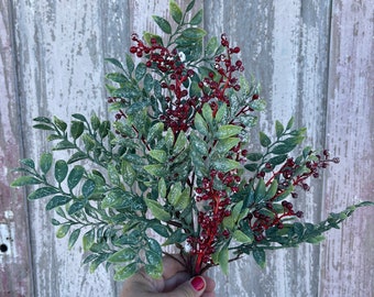 May include: A sprig of faux greenery with red berries and a dusting of white, resembling snow. The greenery has a frosted appearance.